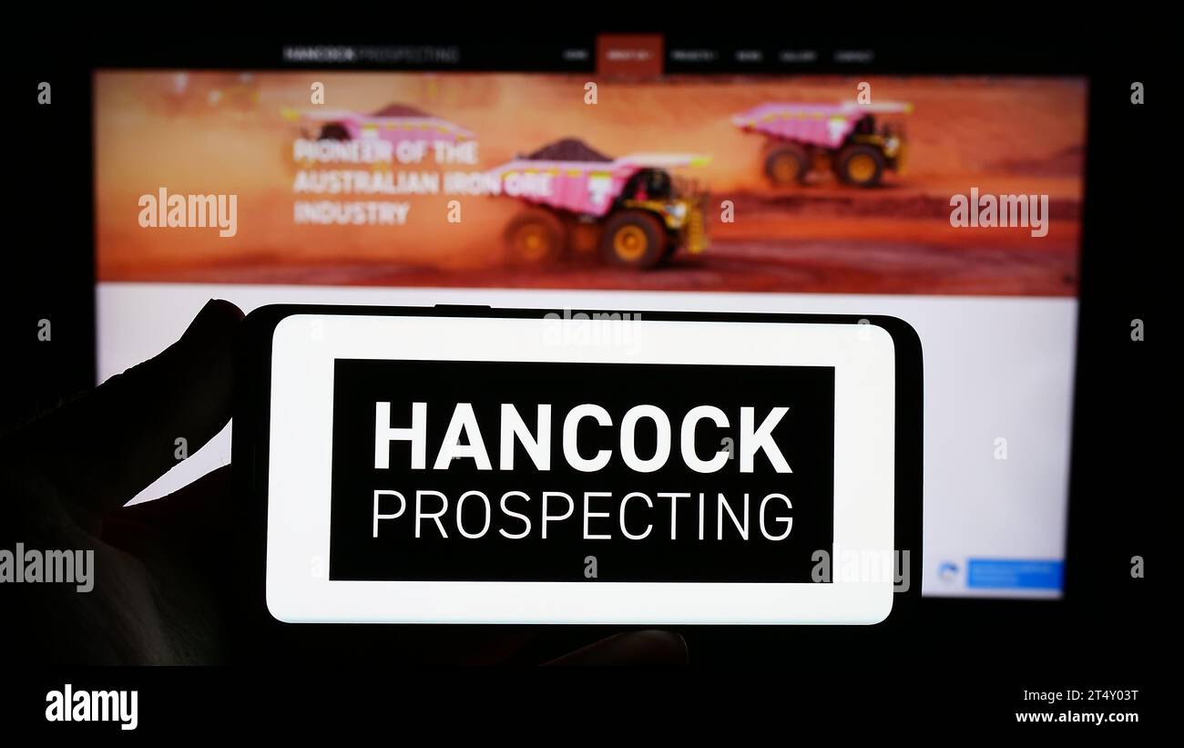 Persona che possiede uno smartphone con il logo della società mineraria australiana Hancock Prospecting Pty. Ltd. Davanti al sito Web. Concentrarsi sul display del telefono. Foto Stock