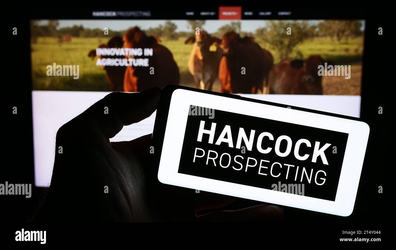 Persona che possiede un telefono cellulare con il logo della società mineraria australiana Hancock Prospecting Pty. Ltd. Davanti alla pagina Web. Concentrarsi sul display del telefono. Foto Stock