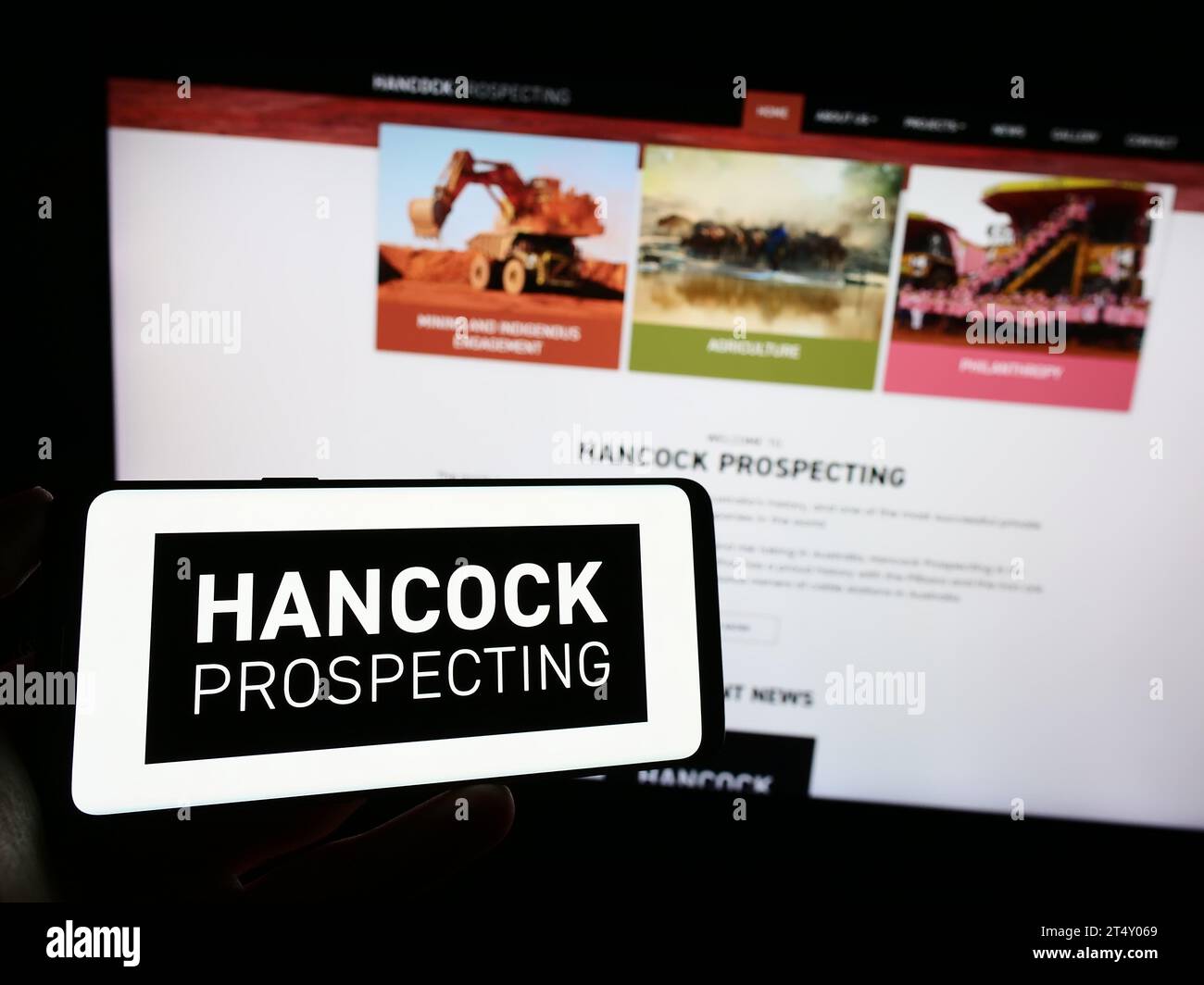 Persona che tiene il cellulare con il logo della società mineraria australiana Hancock Prospecting Pty. Ltd. Davanti alla pagina Web. Concentrarsi sul display del telefono. Foto Stock