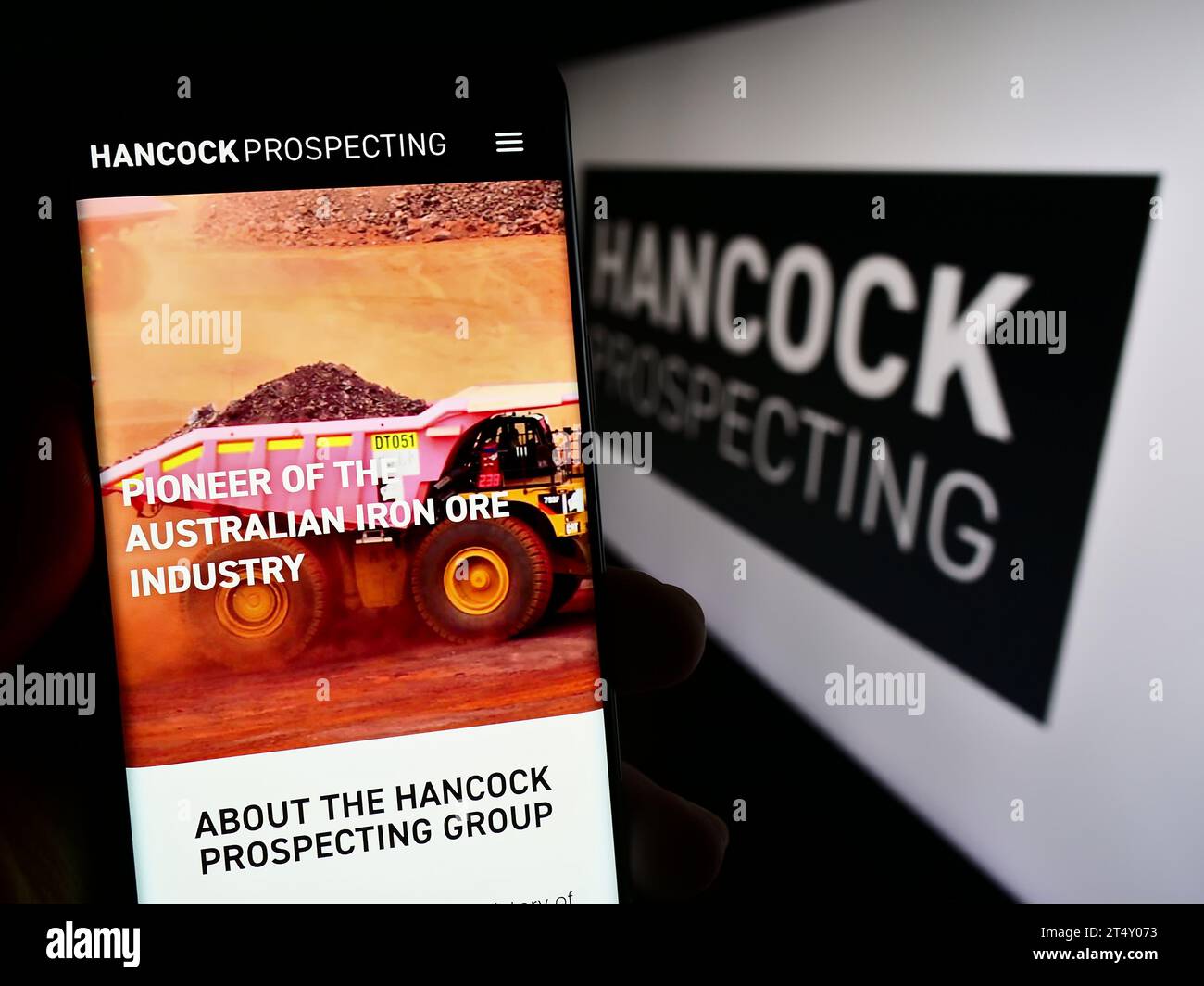 Persona in possesso di cellulare con pagina Web della società mineraria australiana Hancock Prospecting Pty. Ltd. Con logo. Concentrarsi sul centro del display del telefono. Foto Stock