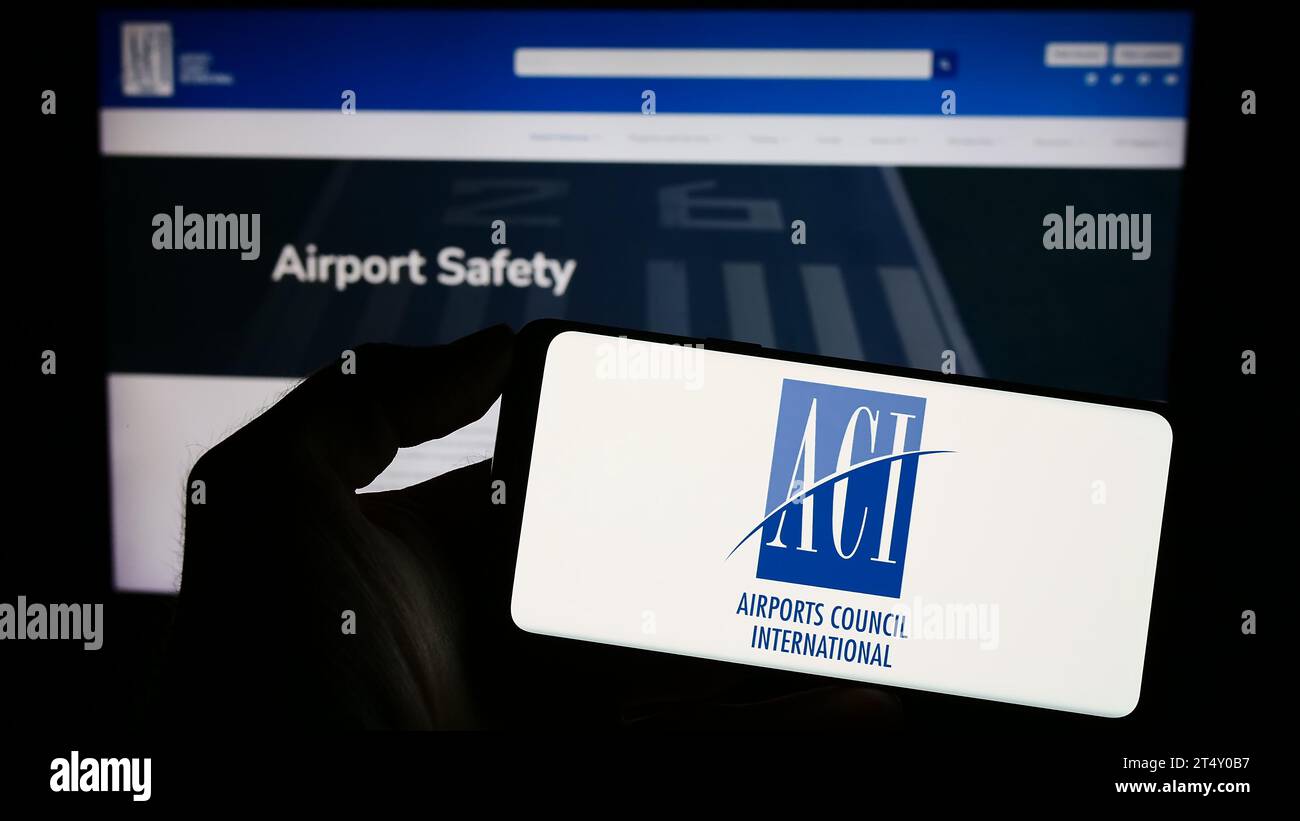 Persona che possiede un telefono cellulare con il logo dell'organizzazione Airports Council International (ACI) davanti alla pagina web. Concentrarsi sul display del telefono. Foto Stock