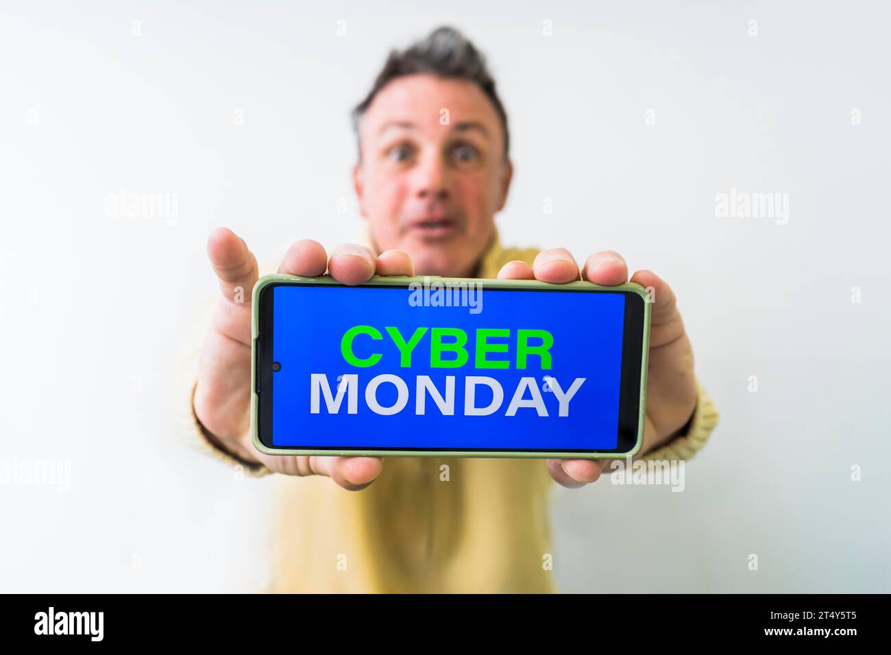 Pazzo che tiene in mano il cellulare con la pubblicità del Cyber Monday sullo schermo Foto Stock