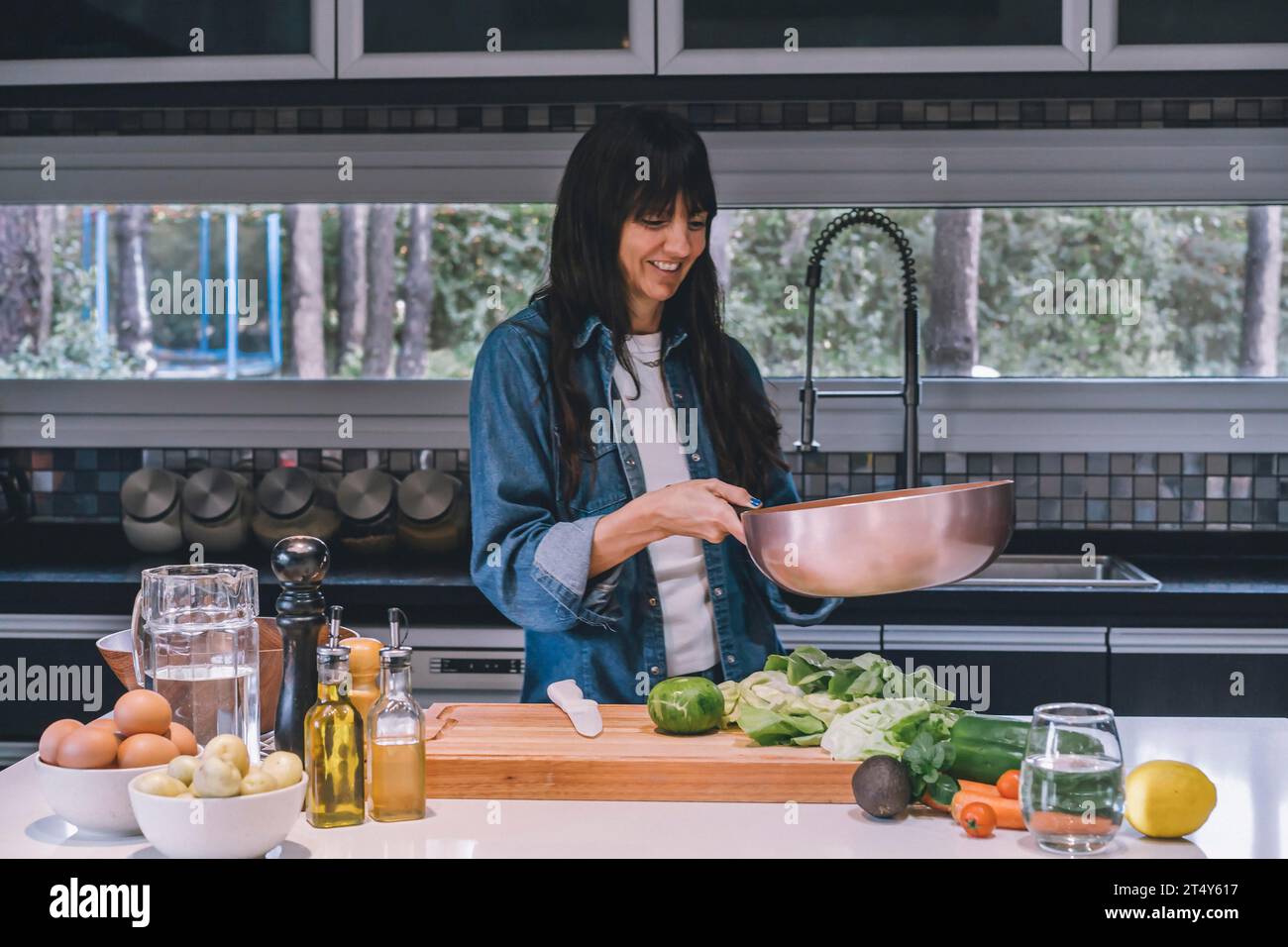 Una donna che cucina verdure in un wok di rame Foto Stock