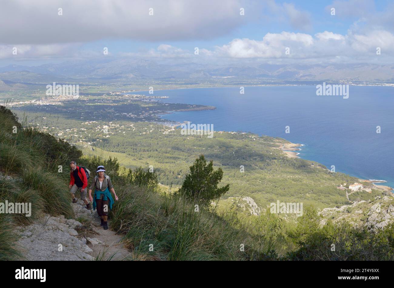 Escursionisti sulla penisola di la Victoria e vista della baia di Pollenca, Maiorca, Isole Baleari, Spagna Foto Stock