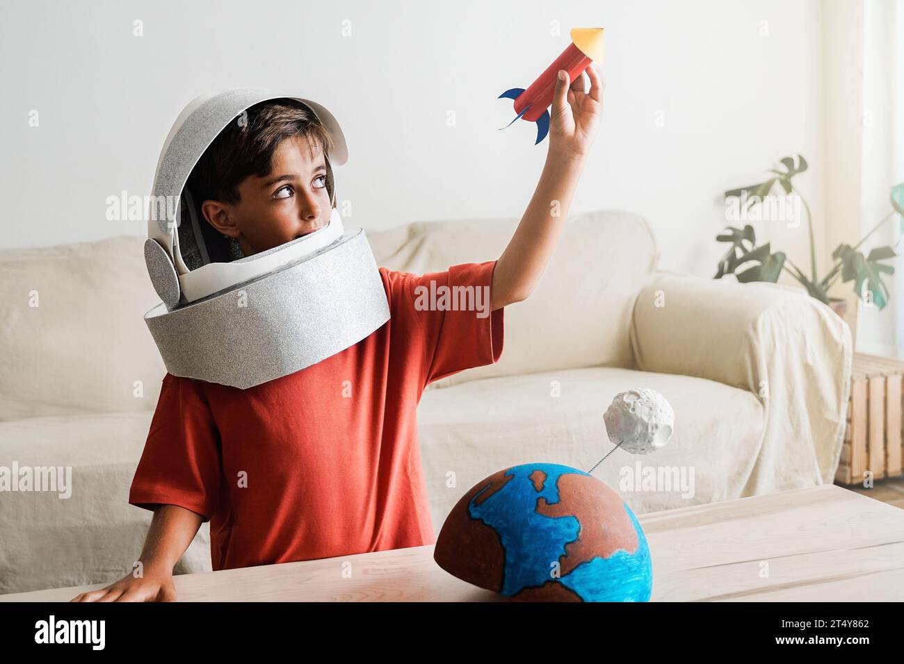 Il bambino astronauta sogna di viaggiare nello spazio con un'astuta astronauta a casa: Un ragazzo felice che gioca ed esplora la galassia Foto Stock