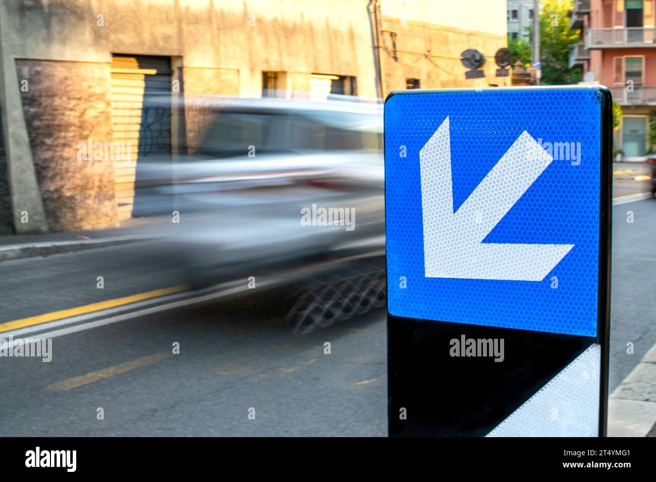 Il movimento dei segnali stradali mostra la direzione con l'auto in movimento dietro sfocata Foto Stock