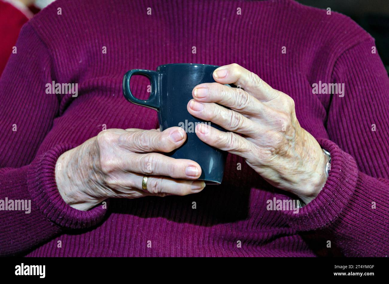 Primo piano di una donna anziana che tiene una tazza di caldo caffè Foto Stock