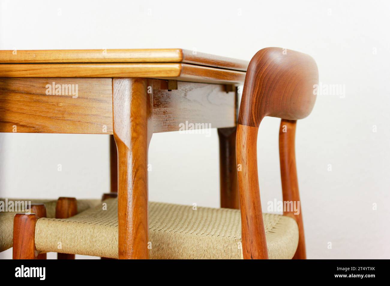 Un tavolo da pranzo in teak della metà del secolo con quattro sedie degli anni '50 '60, design danese, cucina d'epoca, legno massello, antiquariato moderno degli anni '50 e '60 isolato su wal bianco Foto Stock