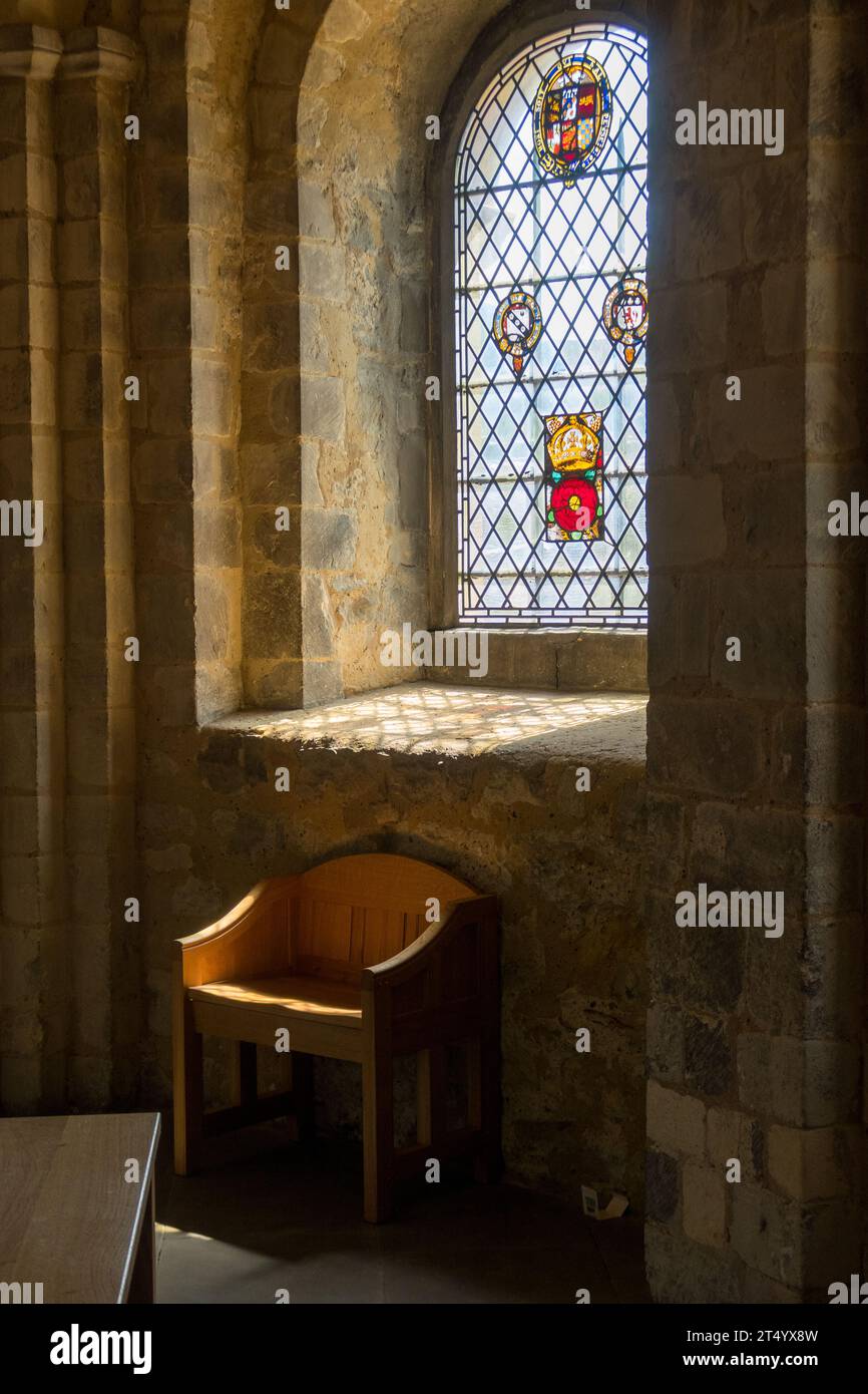 Sedia di fronte a una vetrata colorata in St. John's Chapel, situata nella Torre di Londra. Foto Stock