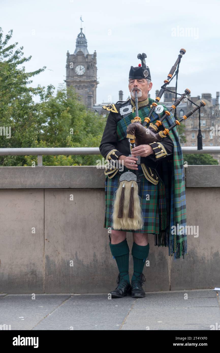 Bagpiper scozzese in una strada a Edimburgo, Scozia, Regno Unito. Il Balmoral Hotel appare dietro di lui. Foto Stock