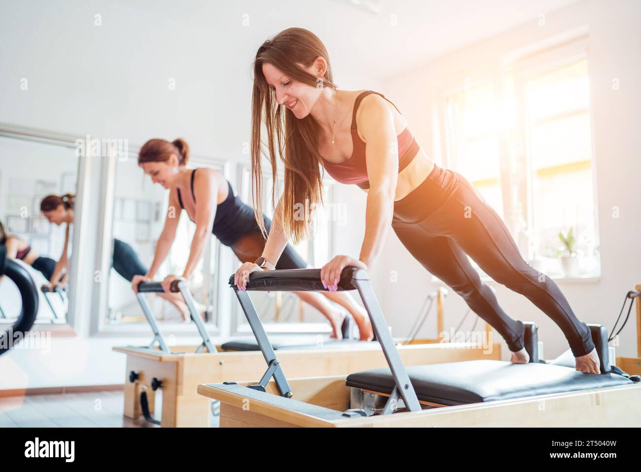 Due giovani femmine che fanno esercizio estensivo dei muscoli muscolari muscolari muscolari muscolari con la macchina riformatrice pilates nella palestra atletica sportiva. pe attivo Foto Stock