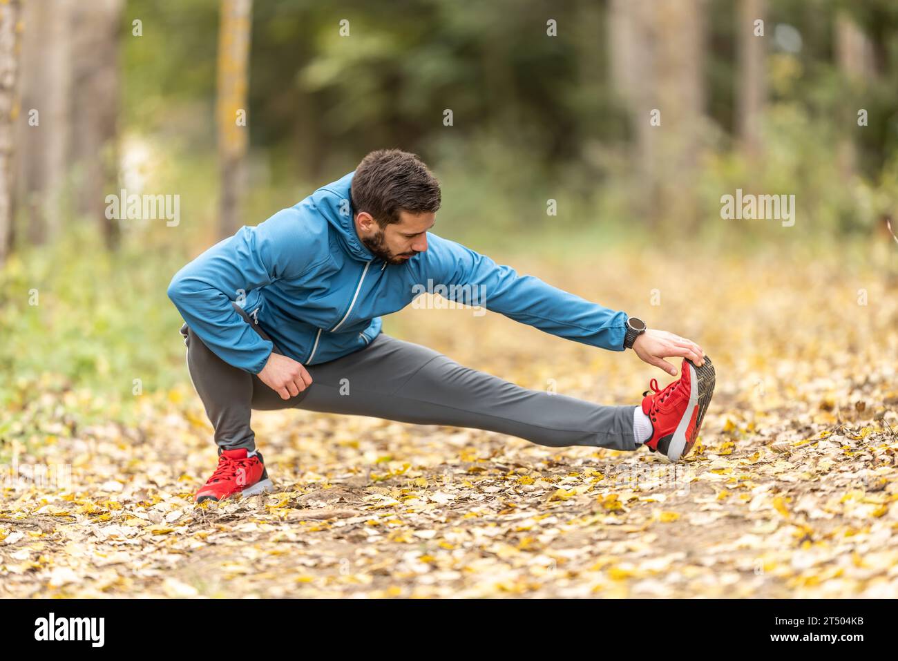 Un giovane atleta si sta riscaldando prima di allenarsi nel parco. Riscalda la parte inferiore del corpo. Foto Stock