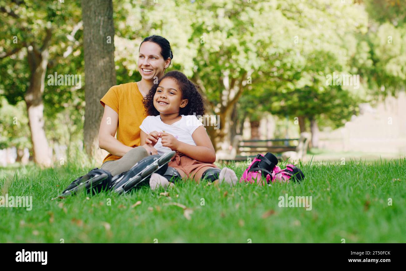 Famiglia, madre e bambino nel parco con pattinaggio a rotelle all'aperto, rilassati sull'erba e divertiti nella natura con persone felici. Donna, ragazza e fare una pausa, sport Foto Stock