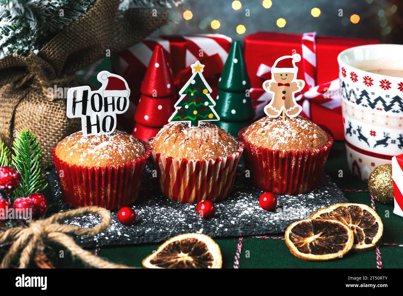 Muffin di natale fatti in casa con divertenti cartelli natalizi e decorazioni natalizie su una tovaglia natalizia. Dolce concetto natalizio Foto Stock