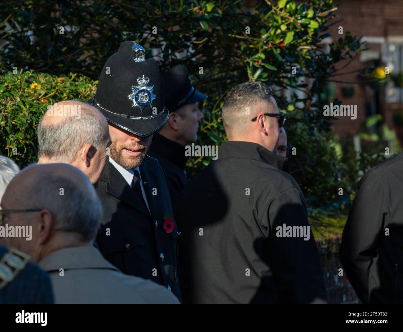 Come parte di una parata domenicale della memoria, un poliziotto barbuto in uniforme, incluso un casco alto tradizionale e in conversazione con un civile Foto Stock