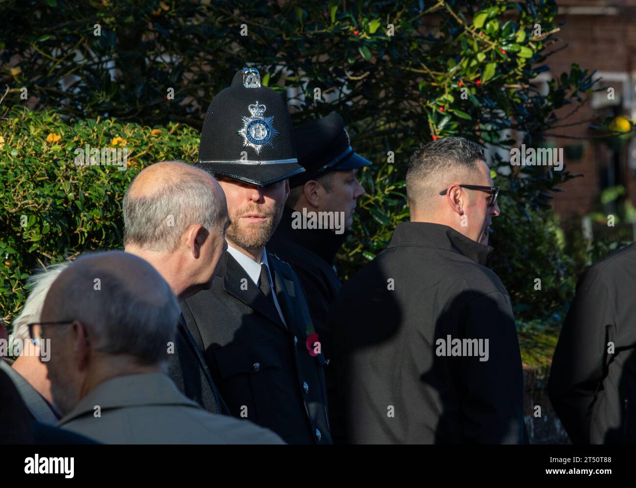 Come parte di una parata domenicale della memoria, un poliziotto barbuto in uniforme, incluso un casco alto tradizionale e in conversazione con un civile Foto Stock