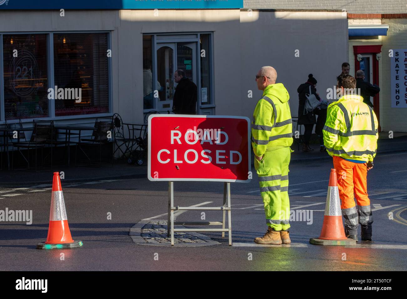 In una città del mercato di Suffolk, due addetti alla gestione del traffico chiudono temporaneamente una strada per una parata domenicale della memoria. Foto Stock