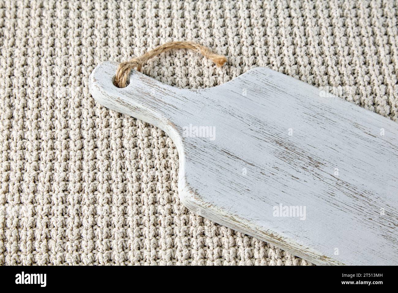 Tagliere di legno bianco vuoto su copriletto a scacchi grezzi a maglia. Modello per menu cibo Foto Stock