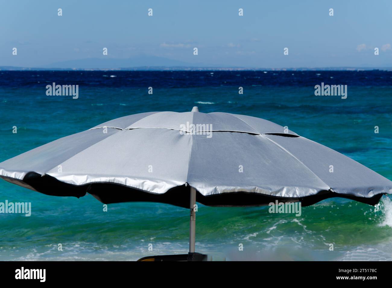 ombrellone silver contro il mare e il vento. Primo piano, sfondo, spazio di copia, orizzonte e cielo Foto Stock