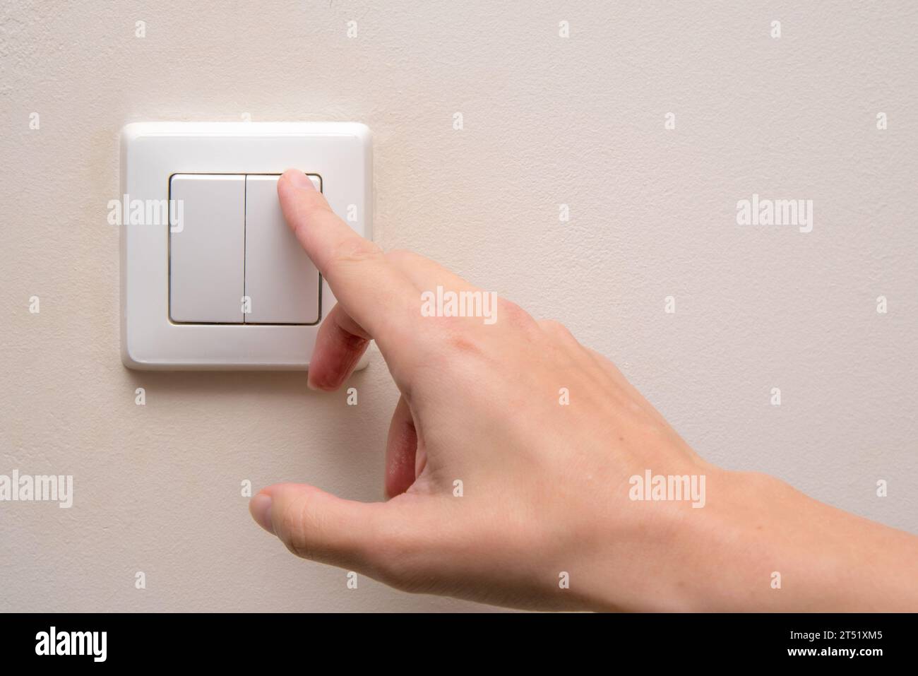 La donna accende un interruttore di luce all'interno di un salotto Foto Stock