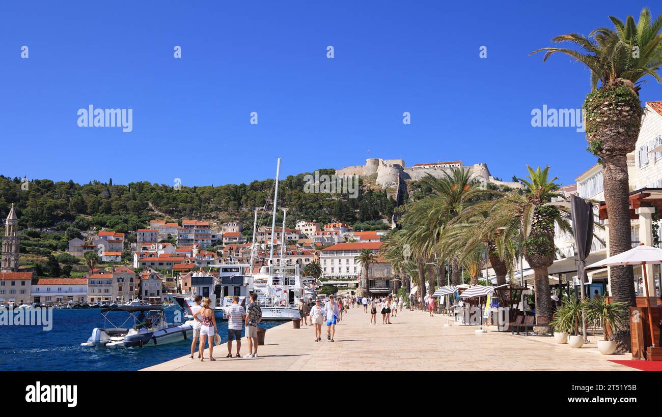 Turisti che si godono Hvar, compreso il porto e la fortezza sulla collina, in Croazia Foto Stock