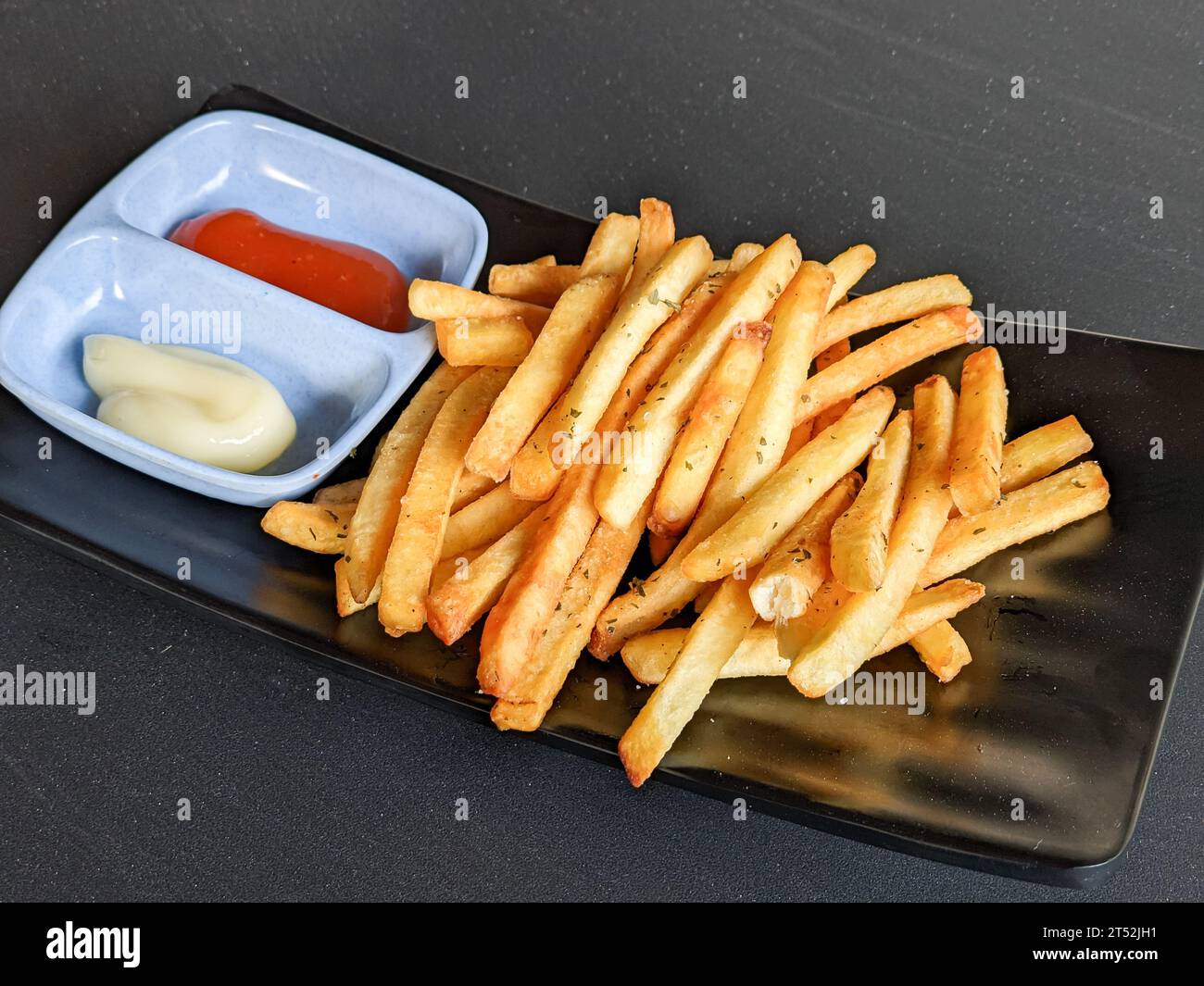 patatine fritte con salsa e maionese su sfondo nero Foto Stock