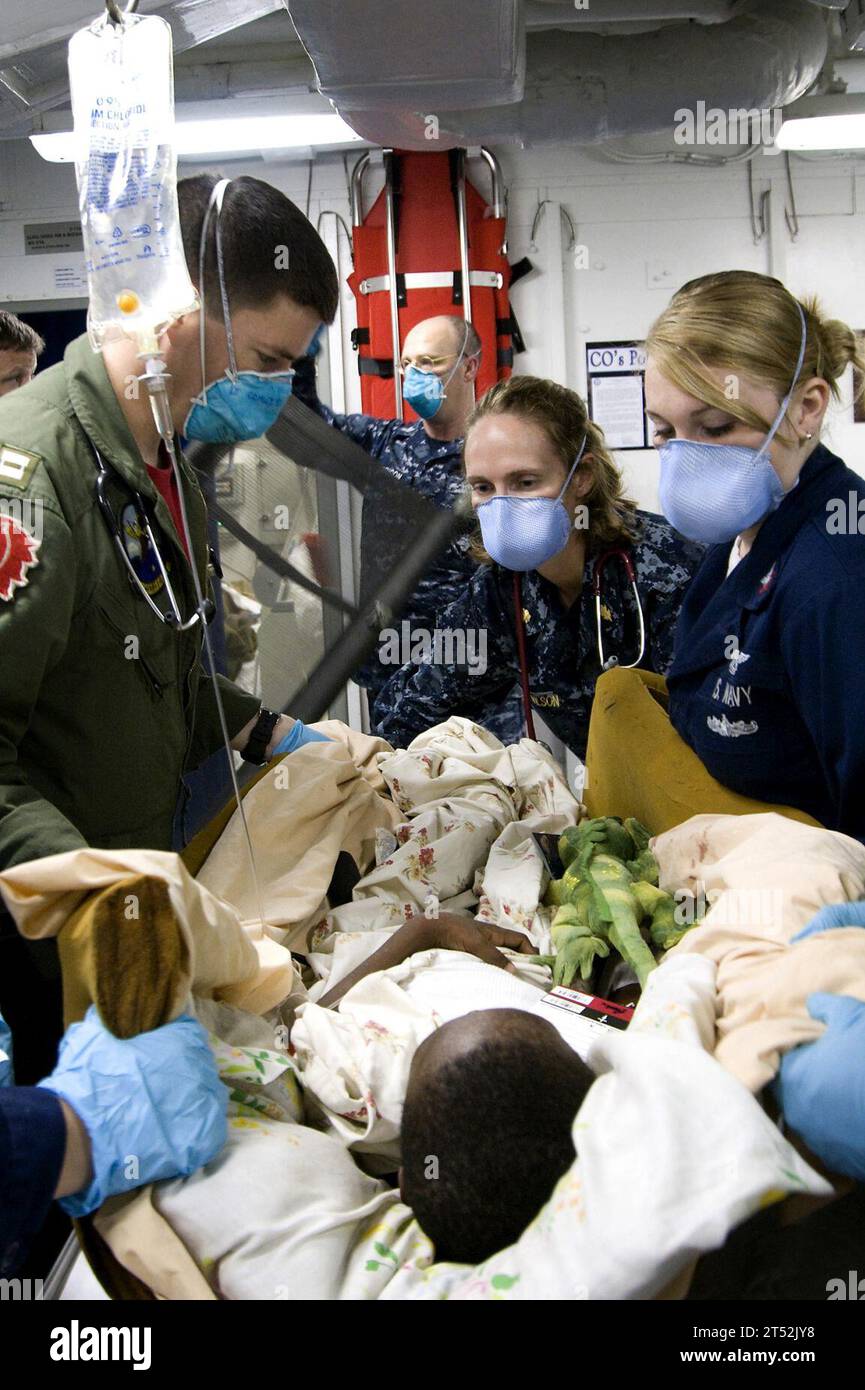 1001218663Y-065 PORT-AU-PRINCE, Haiti (21 gennaio 2010) i medici e i corpi d'ospedale a bordo della portaerei USS Carl Vinson (CVN 70) pongono un ragazzo haitiano ferito su un tavolo per la valutazione. Carl Vinson e Carrier Air Wing (CVW) 17 stanno conducendo operazioni umanitarie e di soccorso in caso di catastrofi nell'ambito dell'operazione Unified Response dopo che un terremoto di magnitudo 7,0 ha causato gravi danni nei pressi di Port-au-Prince il 12 gennaio 2010. Marina Foto Stock