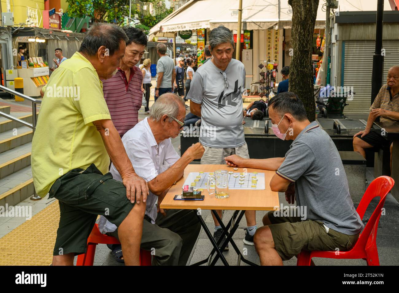 Uomini etnici cinesi che giocano a giochi da tavolo per strada con un pubblico, Chinatown, Singapore Foto Stock