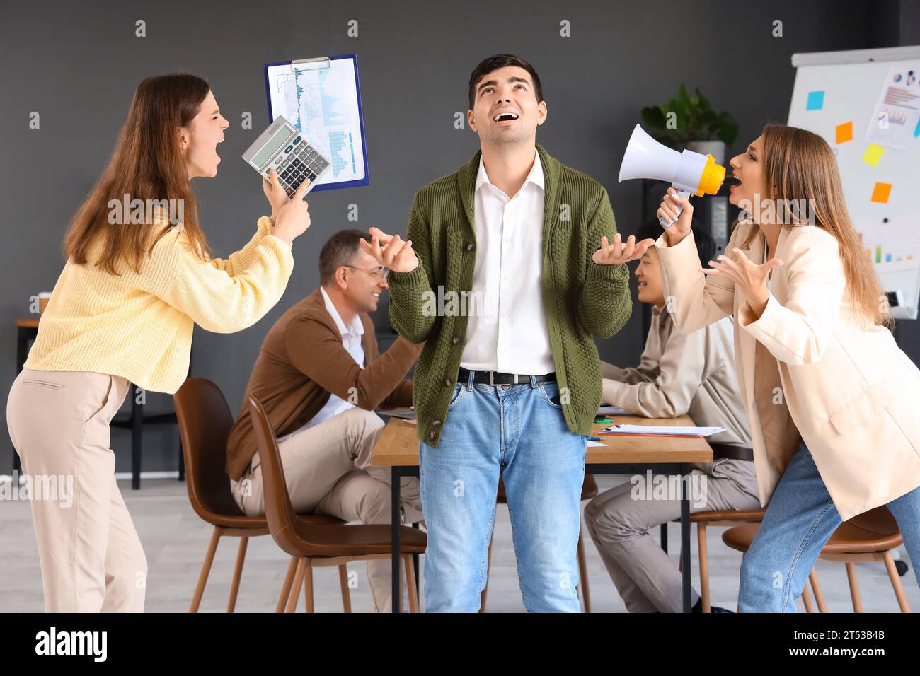 Giovane uomo d'affari che soffre di colleghi rumorosi in ufficio Foto Stock