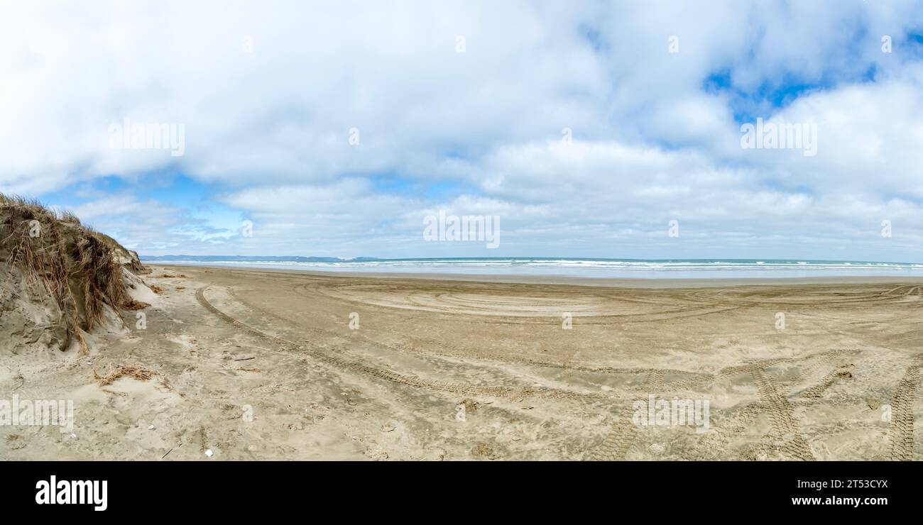 Sandy Beachscape di Ninety Mile Beach, nuova Zelanda, con piste di pneumatici che conducono all'infinito Horizon of Northland's Natural Beauty, ideale per l'estate Foto Stock