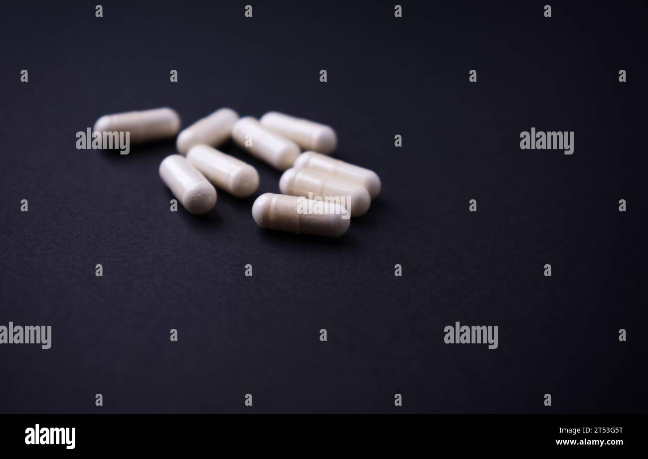 Capsule di arginina alfa-chetoglutarato (AAKG). Integratori alimentari per bodybuilding su fondo di carta scura. Messa a fuoco morbida. Primo piano. Copia spazio. Foto Stock