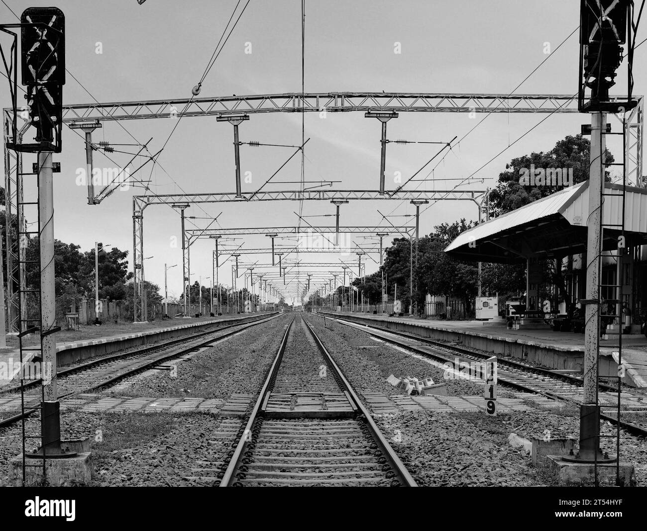 Binari che attraversano una stazione ferroviaria vuota con più archi metallici in fila che fissano i cavi elettrici ad alta tensione Foto Stock