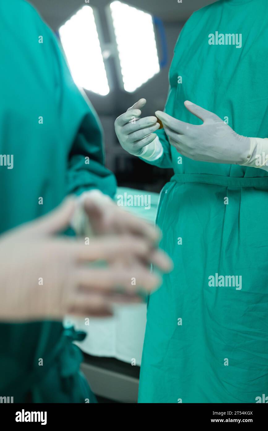 Sezione intermedia di diversi chirurghi che indossano abiti chirurgici in sala operatoria all'ospedale Foto Stock