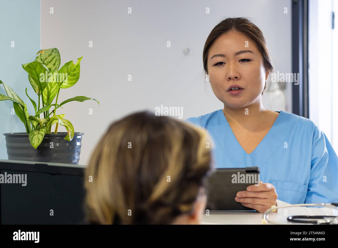 Medico femminile diversificato con tablet e receptionist che parla alla reception dell'ospedale, spazio copia Foto Stock