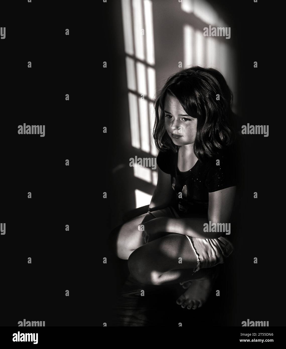 Bella bambina seduta nell'ombra Foto Stock