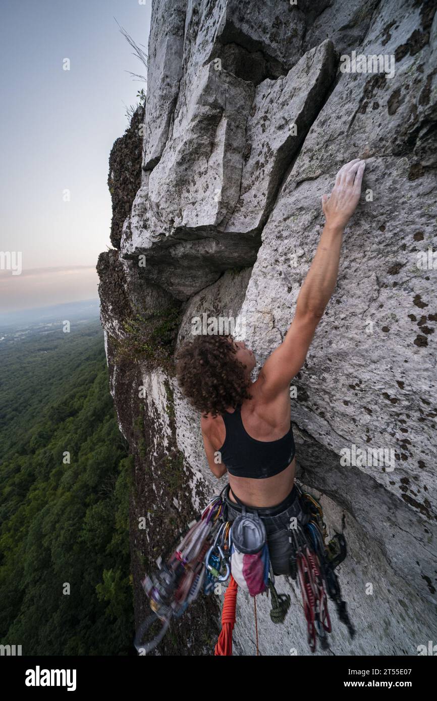 Rock Climbing Woman Leading at Sunset Foto Stock