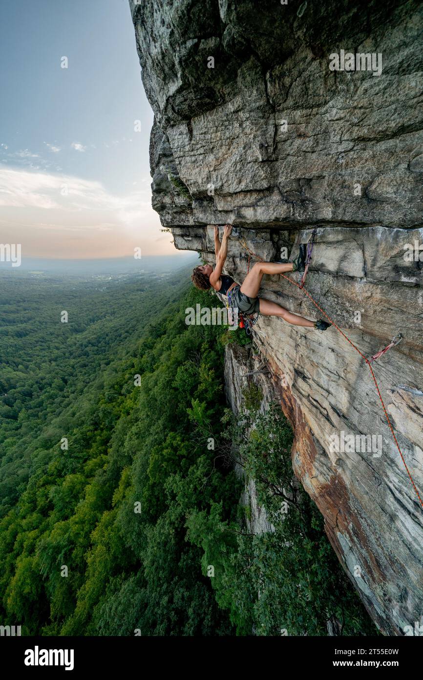 Rock Climbing Woman Leading at Sunset Foto Stock