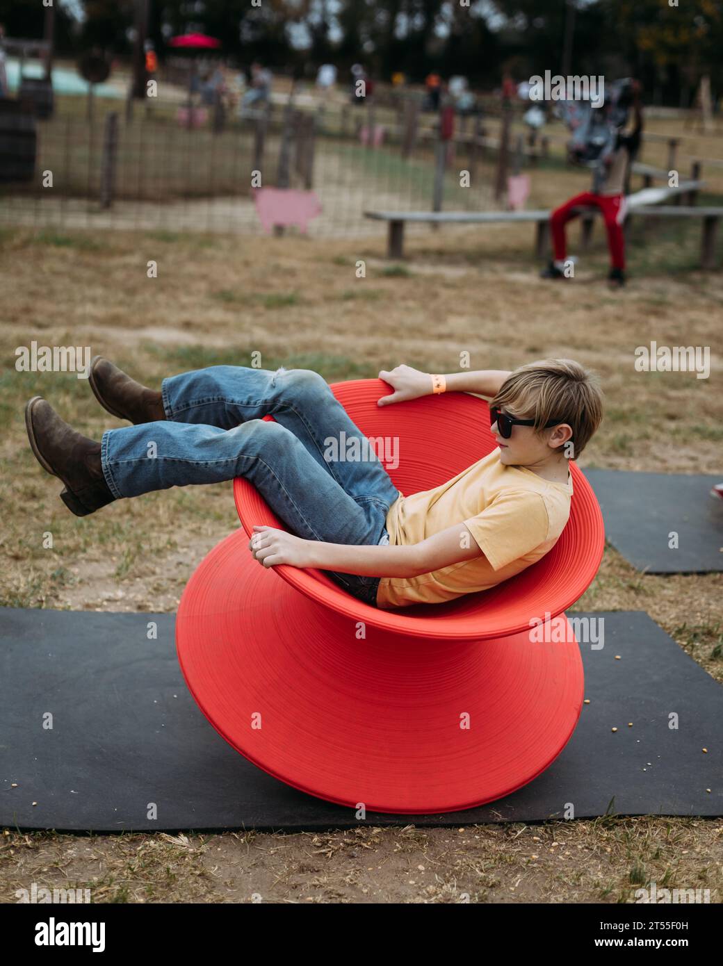 Ragazzo che gioca con la sedia rotante sul parco giochi Foto Stock