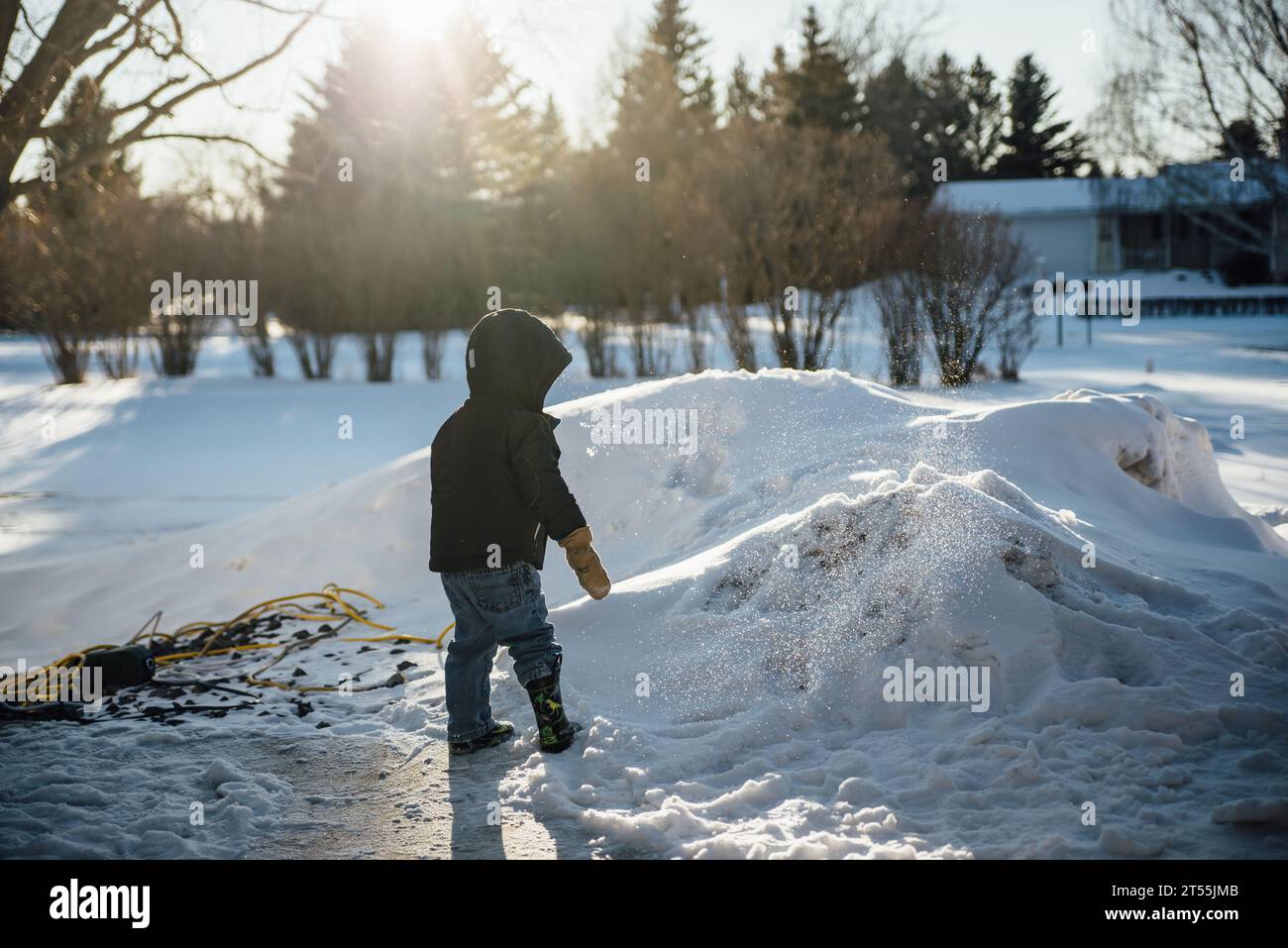 Vista posteriore del bambino in piedi di fronte al cumulo di neve nel cortile W. Foto Stock