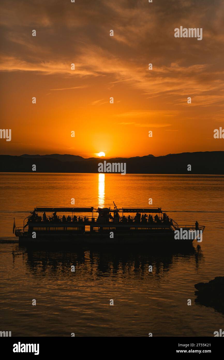 Grande imbarcazione da trasporto dalla silhouette con il sole sullo sfondo Foto Stock