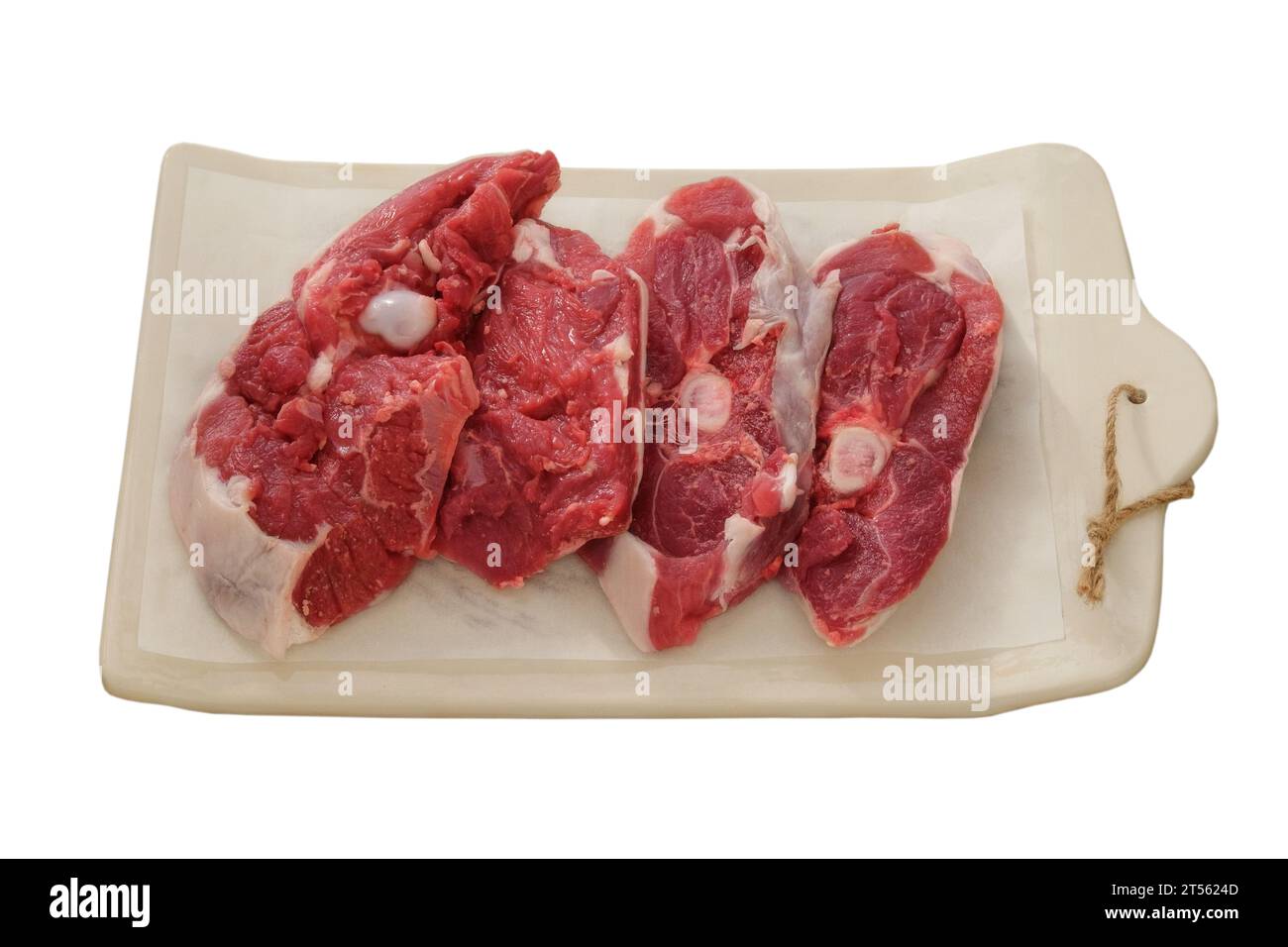Carne di agnello su un pannello di ceramica isolato su sfondo bianco. Pezzi di carne per cucinare. Parte posteriore della carcassa di carne. Foto Stock