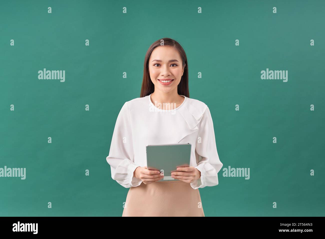 Donna d'affari sorridente e attraente che indossa un dispositivo tablet formale su sfondo verde Foto Stock
