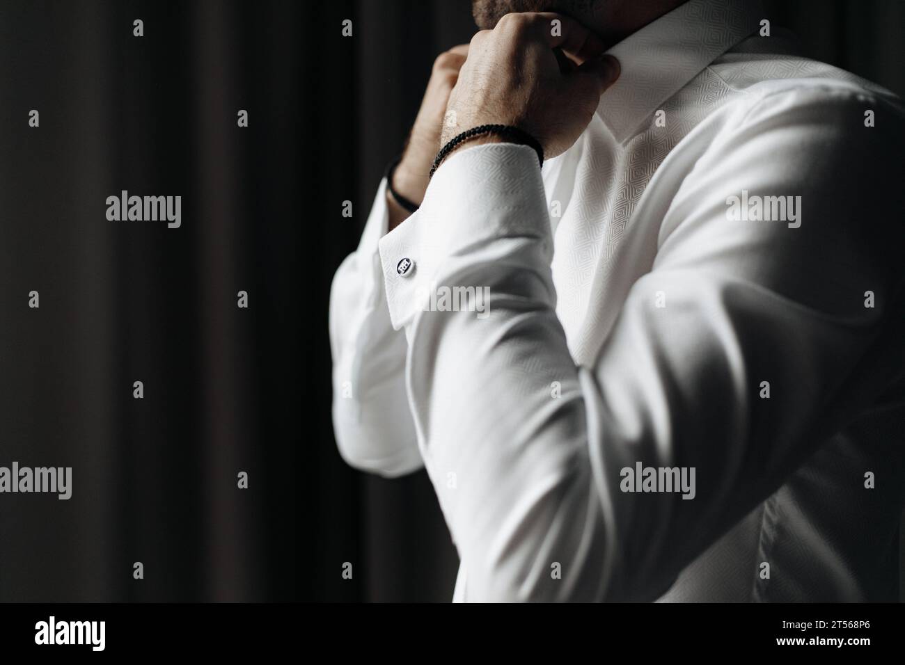 Immagine ravvicinata del collare di regolazione maschio caucasico di una camicia bianca. Sposo che si prepara per il matrimonio. Foto Stock