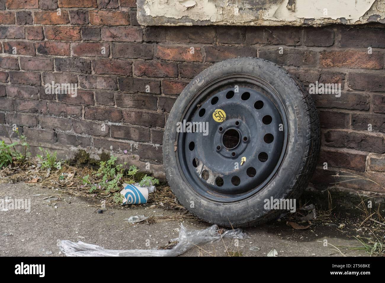 Londra, Inghilterra, 17 luglio 2023. Uno pneumatico nero scartato poggia contro un muro di mattoni intemprati. Lo pneumatico presenta segni visibili di usura e sporcizia. Foto Stock
