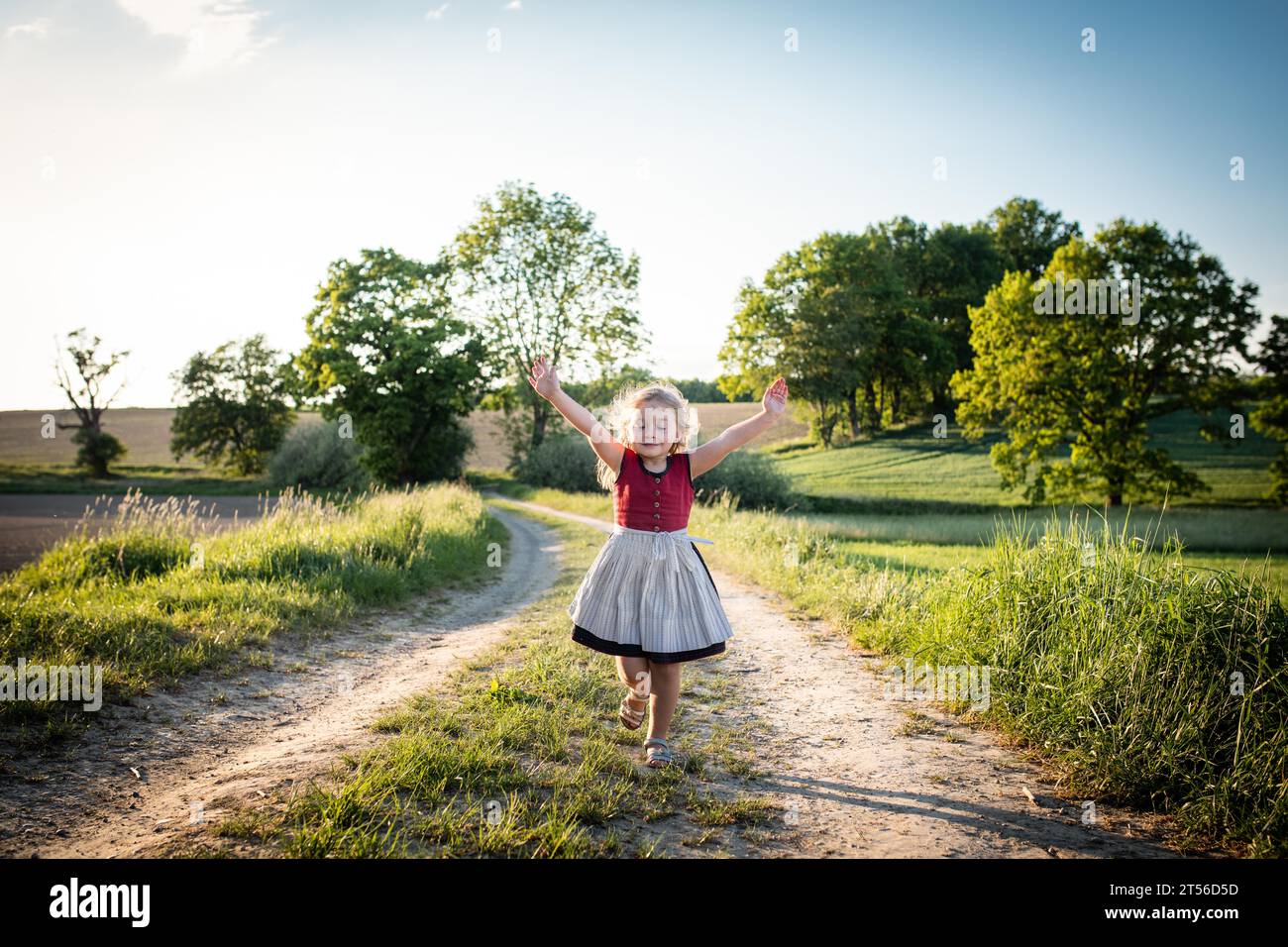 I bambini cantano mentre camminano lungo una strada di campagna, Altomuenster, alta Baviera, Baviera, Germania Foto Stock