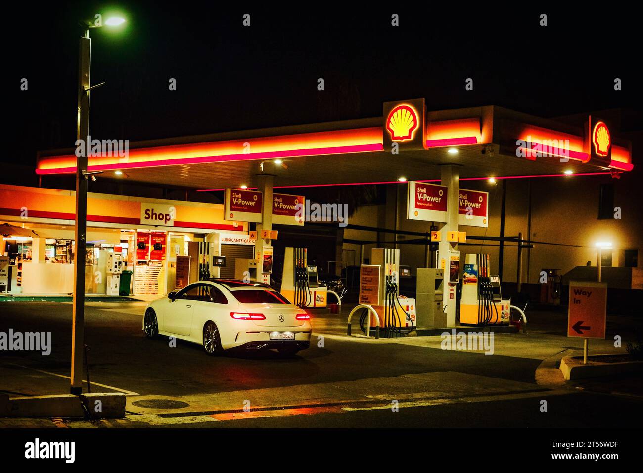 Una berlina bianca è parcheggiata fuori da una stazione di servizio Shell di notte Foto Stock