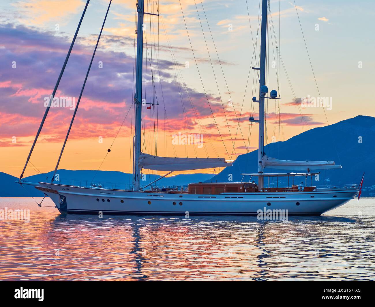 Yacht a vela di 35 metri al tramonto nella baia del Montenegro con colline sullo sfondo. Foto Stock