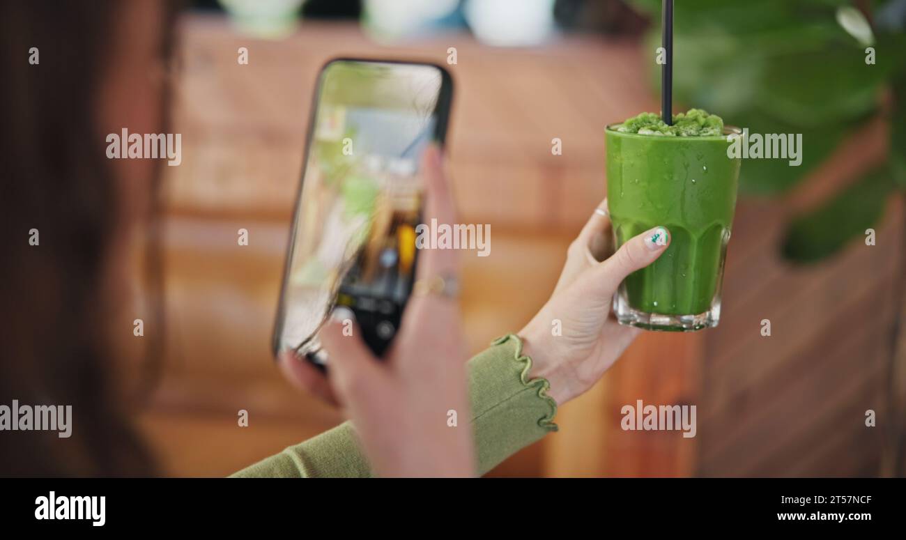 Schermo del telefono, fotografia e succo verde per dieta, donna o bicchiere in caffetteria per l'app social network. Influencer girl, smartphone e frullato in post Foto Stock
