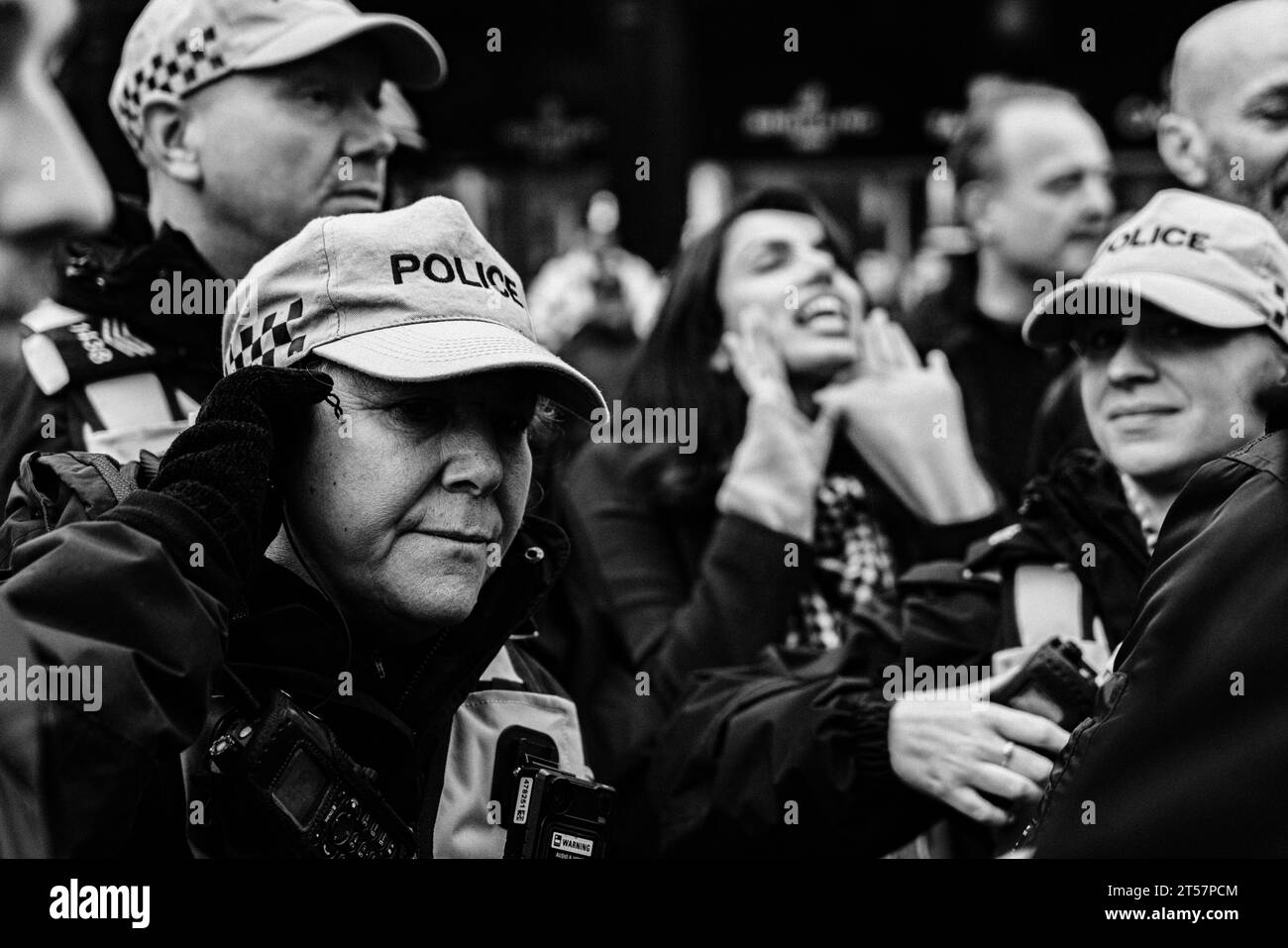 Newcastle upon Tyne, Inghilterra, Regno Unito - ottobre 28 2023. La polizia britannica in uniforme ascolta l'auricolare mentre i manifestanti gridano sullo sfondo. Foto Stock