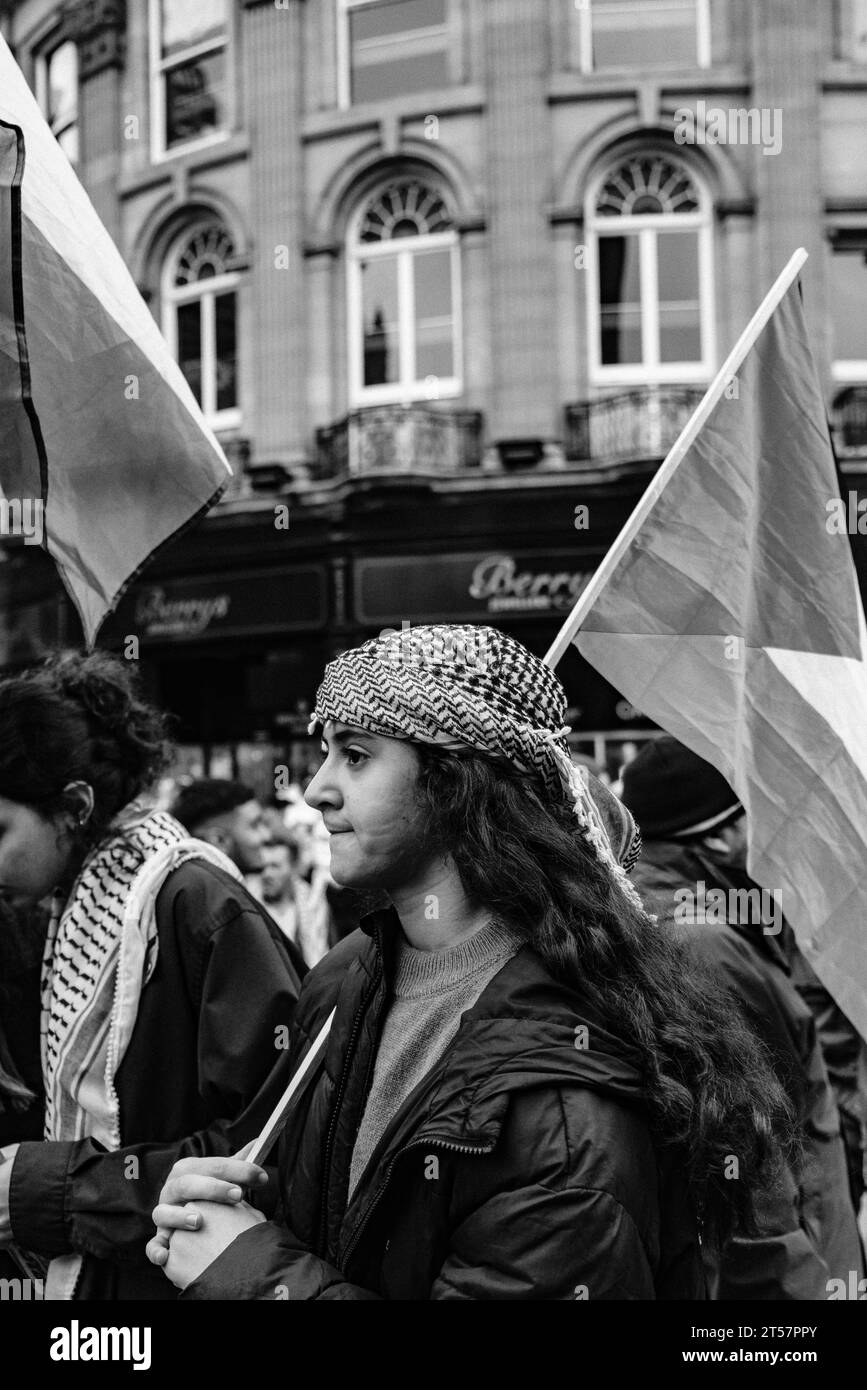 Giovane che indossa un keffiyeh che sventola la bandiera palestinese nel centro della città, la marcia per il cessate il fuoco a Gaza. Newcastle upon Tyne, Inghilterra, Regno Unito - ottobre 28 2023 Foto Stock